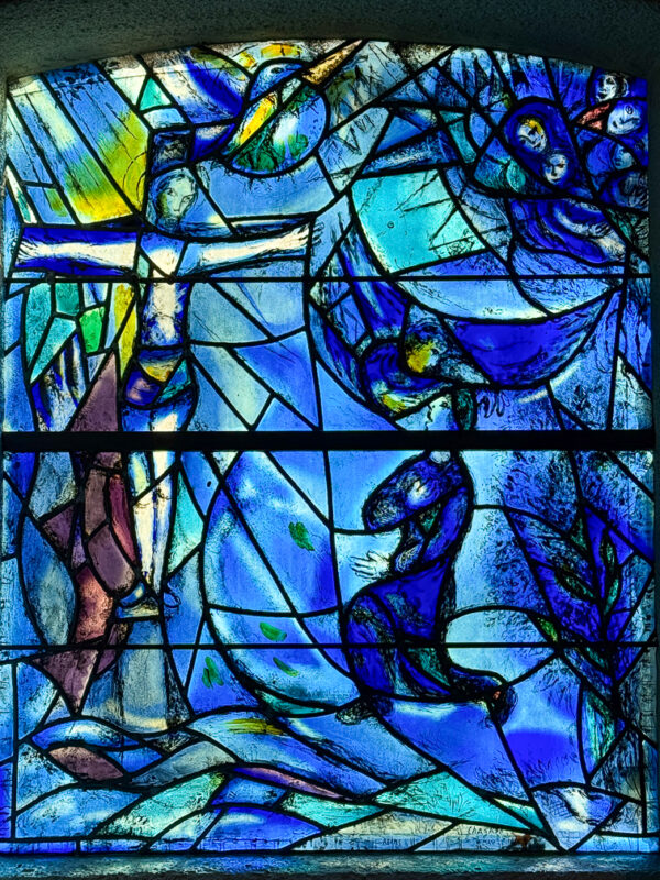 The Crucifixion window by Marc Chagall, featuring symbolic water motifs and vibrant blues representing loss and spirituality.