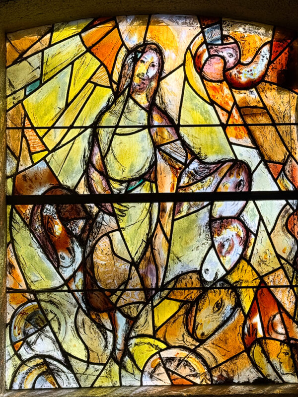The Prophet Elijah window by Marc Chagall, glowing with vivid yellows and dynamic figures, depicting Elijah’s dramatic ascension to heaven.