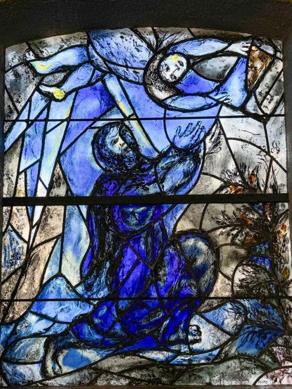 Image on stage glass created by Marc Chagall shows the Prophet Ezekiel reaching up to Heaven and receiving a book from an angel.