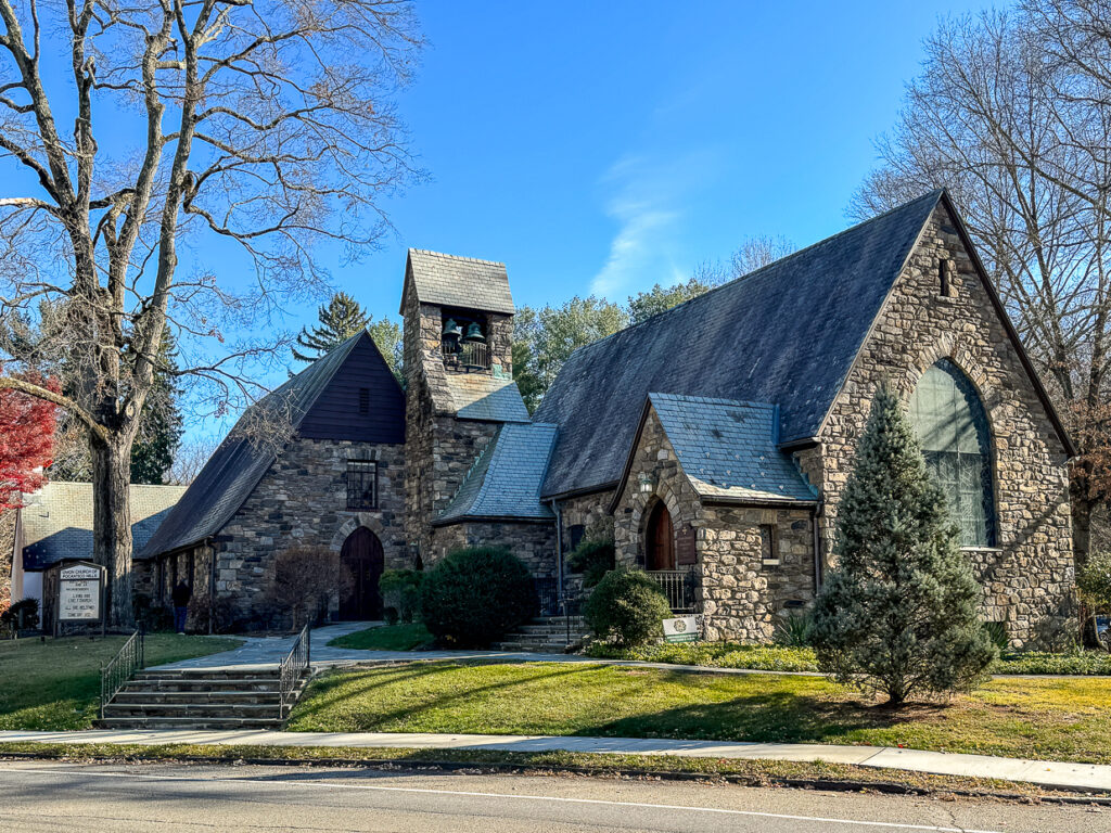 Exterior of the Union Church of Pocantico Hills, showcasing fieldstone facade and steep slate roof.