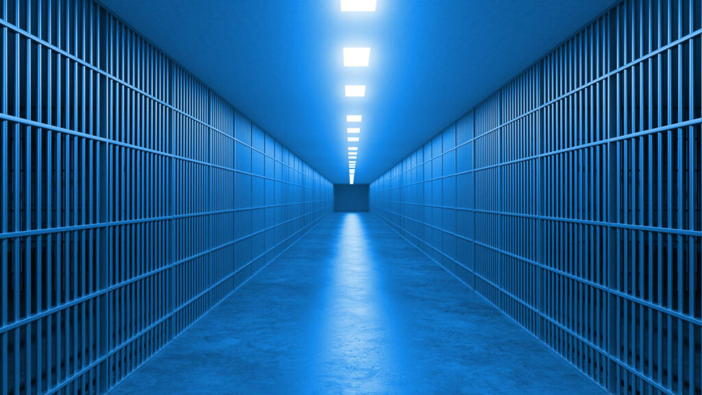 Inside Manhattan Night Court: A Visitor’s Guide 2 Very long jail corridor with barred cells and blue overhead lights